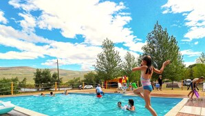 A swimming pool with people enjoying the water, surrounded by a wooden deck and trees. - Mobile House Magoro 5 (Benkovac)