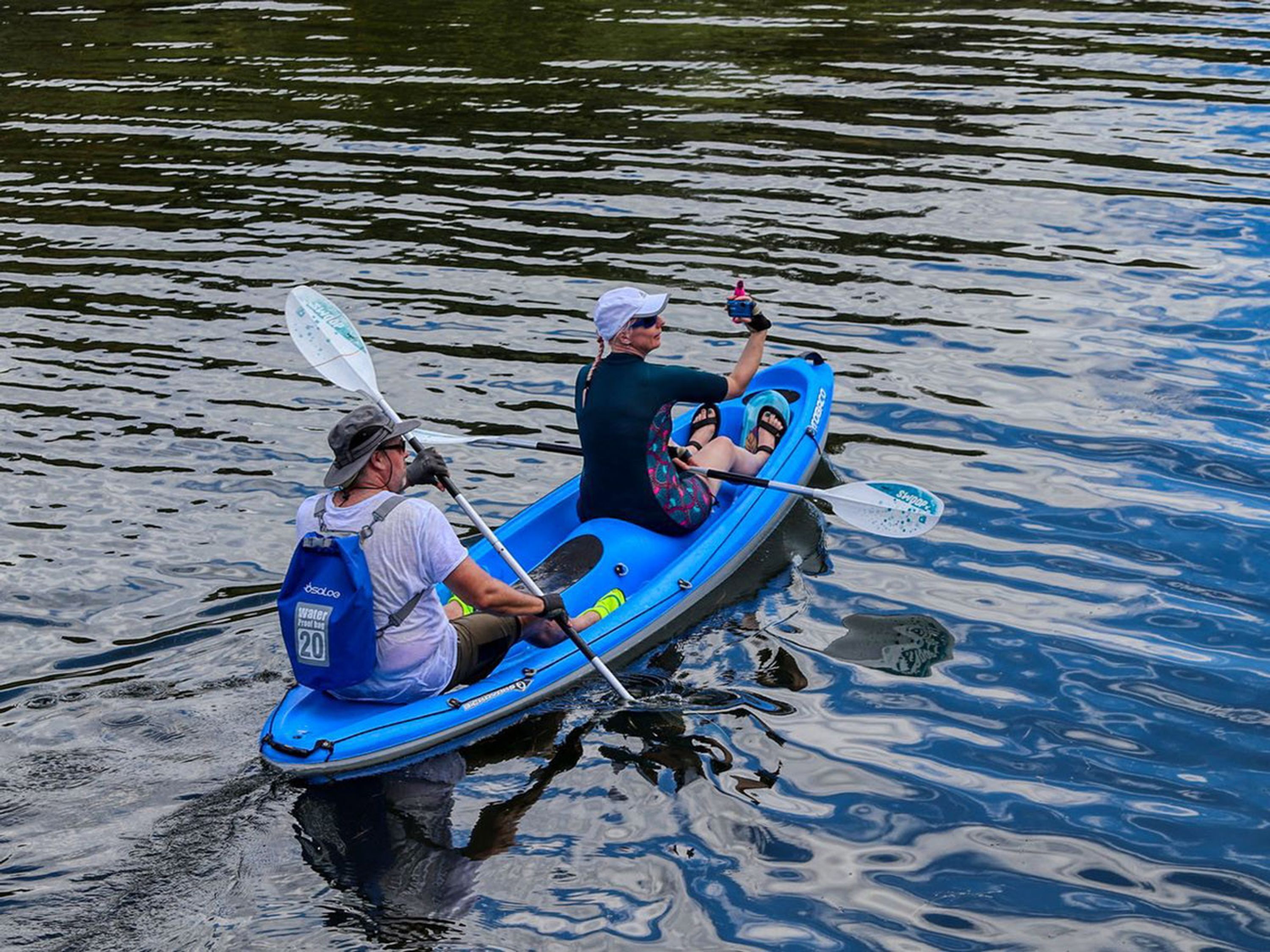 Deux personnes dans un kayak bleu sur une étendue d’eau.