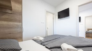 A modern hotel room with a large bed, a wooden wardrobe, a flat-screen TV, and a door leading to another room. - Mobile House Magoro 5 (Benkovac)