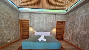 A modern bedroom with a large bed, wooden accents, and a skylight. - Serenity Sand Bungalow (Cahuita)