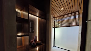 A modern bathroom with wooden shelves, a bench, and a shower area with a wooden lattice partition. - Serenity Sand Bungalow (Cahuita)