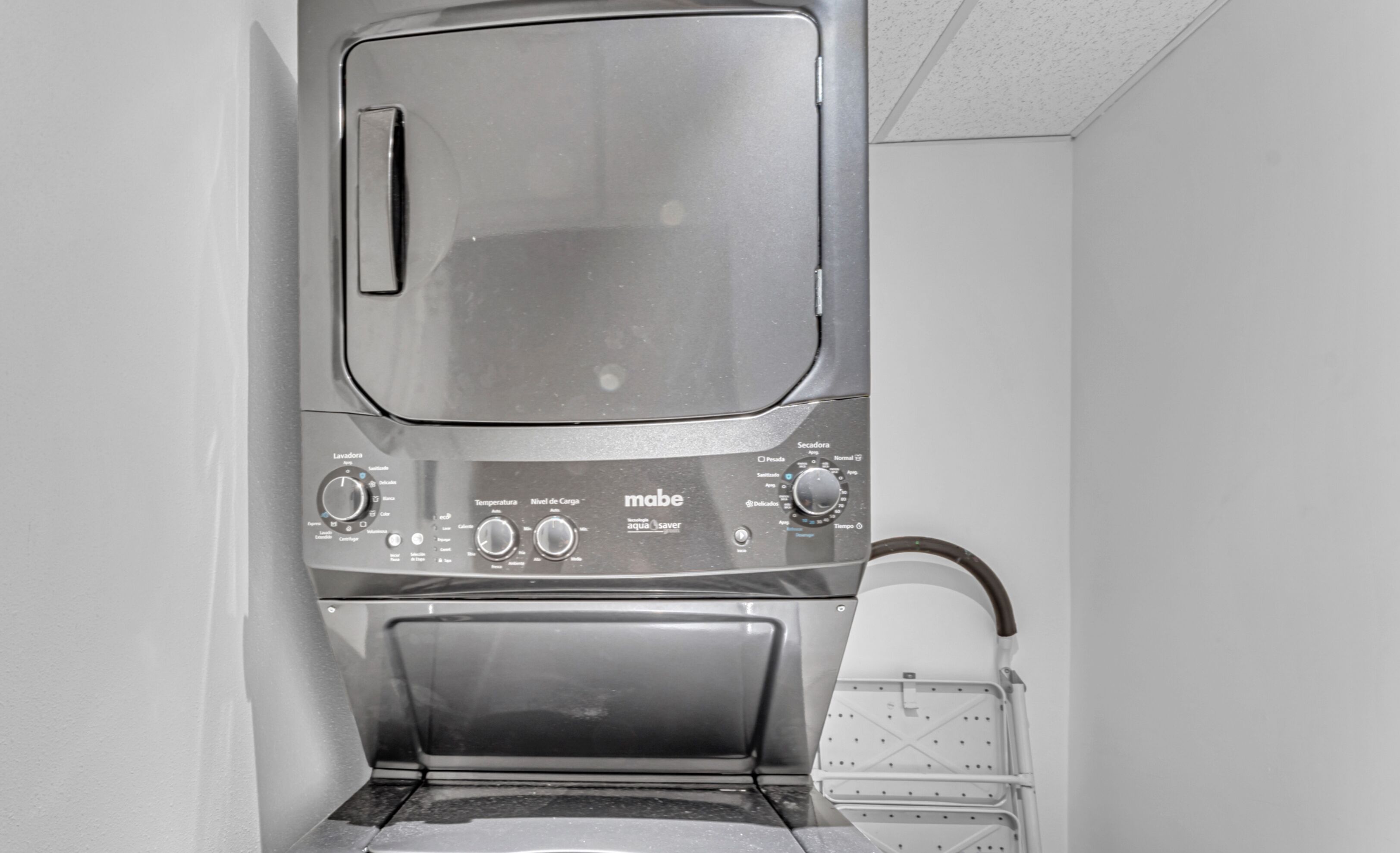 A compact, stainless steel front-loading washer and dryer unit with control knobs and a transparent door.
