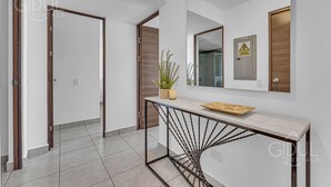 A modern hallway with a console table, a potted plant, and a mirror. - Cozy, Modern, Upscale APT W/Views, Pool, Gym, A/C (San Salvador)