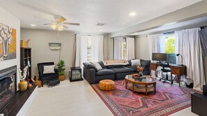 A living room with a fireplace, a sofa, a coffee table, and a desk with a computer. - Woodsy, Quiet Neighborhood, 2 bedroom (Grants Pass)