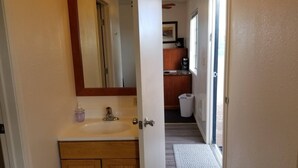 A bathroom with a wooden vanity, a sink, and a mirror. There is a window with a view of the outside. - Affordable Getaway near Grand Canyon Sleeps 4 (Williams AZ 86046)