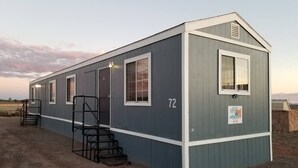 A single-story, grey building with a white trim, labeled with the number 72. It features a set of external stairs leading to a door, and a small window on the upper floor. - Affordable Getaway near Grand Canyon Sleeps 4 (Williams AZ 86046)