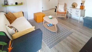 A living room with a sofa, a coffee table, a chair, and a small table with decorative items. There is a door leading to another room. - T2 between sea and pond   (Sète)