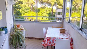 A small balcony with a table and chairs, a potted plant, and a view of greenery. - T2 between sea and pond   (Sète)