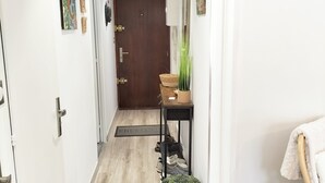 A hallway with a wooden floor, a door at the end, a small table with a plant, and a chair with a towel. - T2 between sea and pond   (Sète)