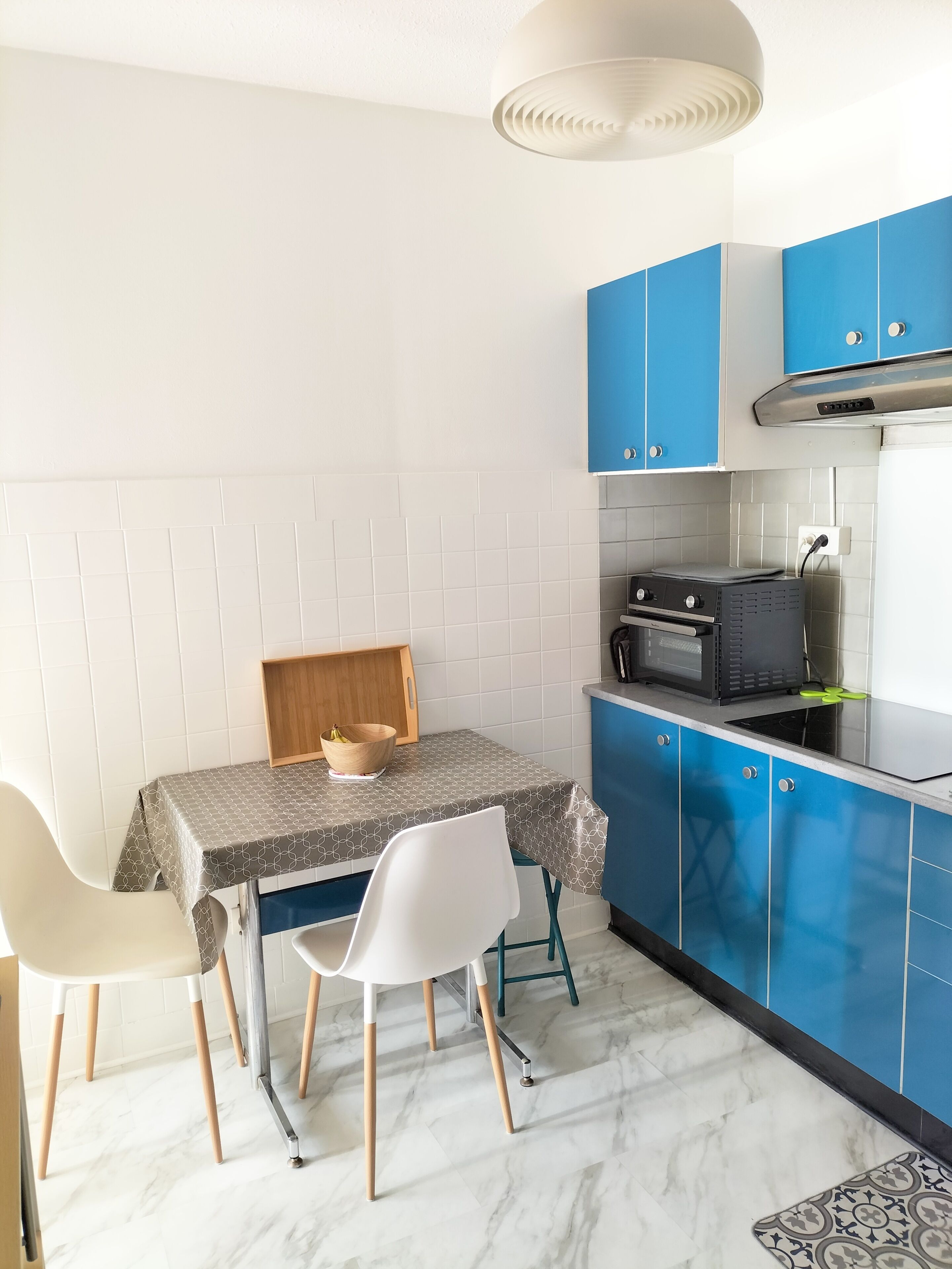 A compact kitchen with blue cabinets, a microwave, and a table with chairs.