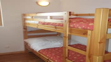 A bunk bed room with wooden frames and red patterned bedding.