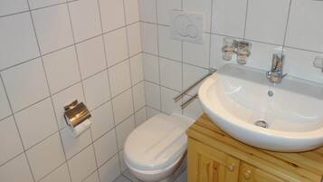Ein kleines Badezimmer mit Toilette, Waschbecken und einem Holzschrank.