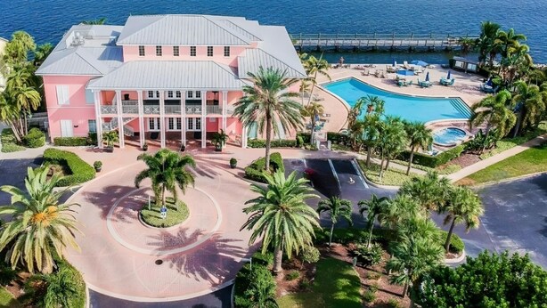 Ein rosafarbenes Resort mit Pool und Palmen.