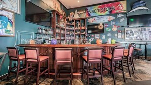 Eine Bar mit einer Holztresen, mehreren Flaschenregalen und Barhocker.