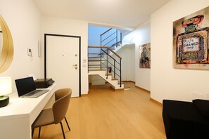 A modern interior with a desk, chair, staircase, and artwork. - La Terrazza del Garraffello (Palermo)
