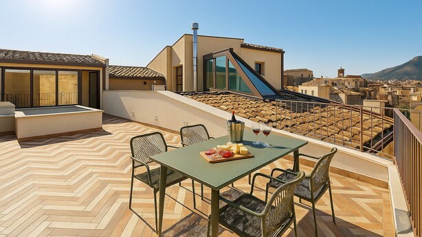 A rooftop terrace with a dining table, chairs, and a view of the cityscape. - La Terrazza del Garraffello (Palermo)