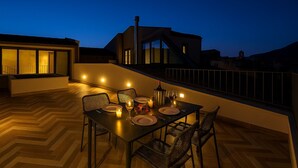 An outdoor dining area with a table set for two, chairs, and a candle on the table. - La Terrazza del Garraffello (Palermo)