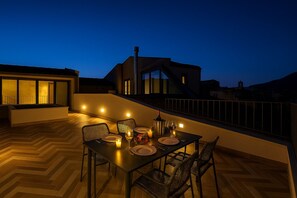 An outdoor dining area with a table set for two, chairs, and a candle on the table. - La Terrazza del Garraffello (Palermo)