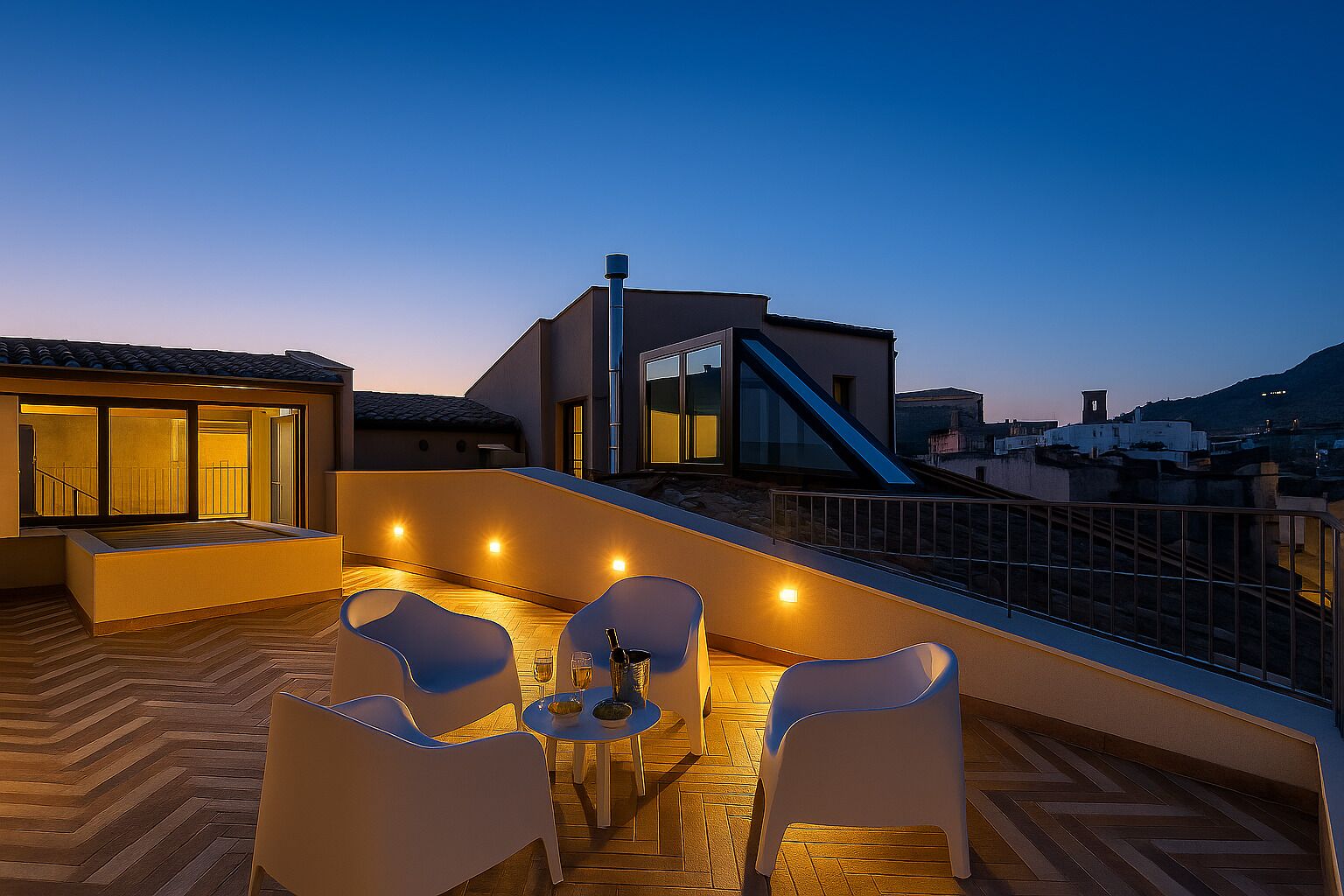 A rooftop terrace with a seating area, a staircase, and a view of the cityscape at dusk.