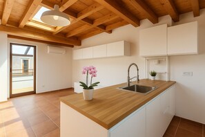 A modern kitchen with a wooden countertop, a sink, and a potted orchid. - La Terrazza del Garraffello (Palermo)