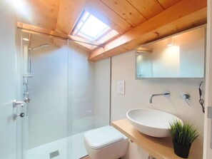 A modern bathroom with a glass shower enclosure, a white toilet, a wooden vanity with a white sink, and a small potted plant. - La Terrazza del Garraffello (Palermo)