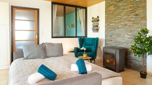 A bedroom with a bed, a chair, a fireplace, and a wall with directional signs. - Magic Mountain breathtaking view of Mt Stmichel Bay (Dragey-Ronthon)