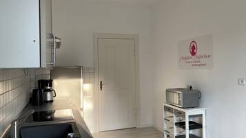Eine moderne Küche mit weißen Schränken, einer schwarzen Arbeitsplatte, einer Kaffeemaschine, einem Toaster und einer weißen Tür.