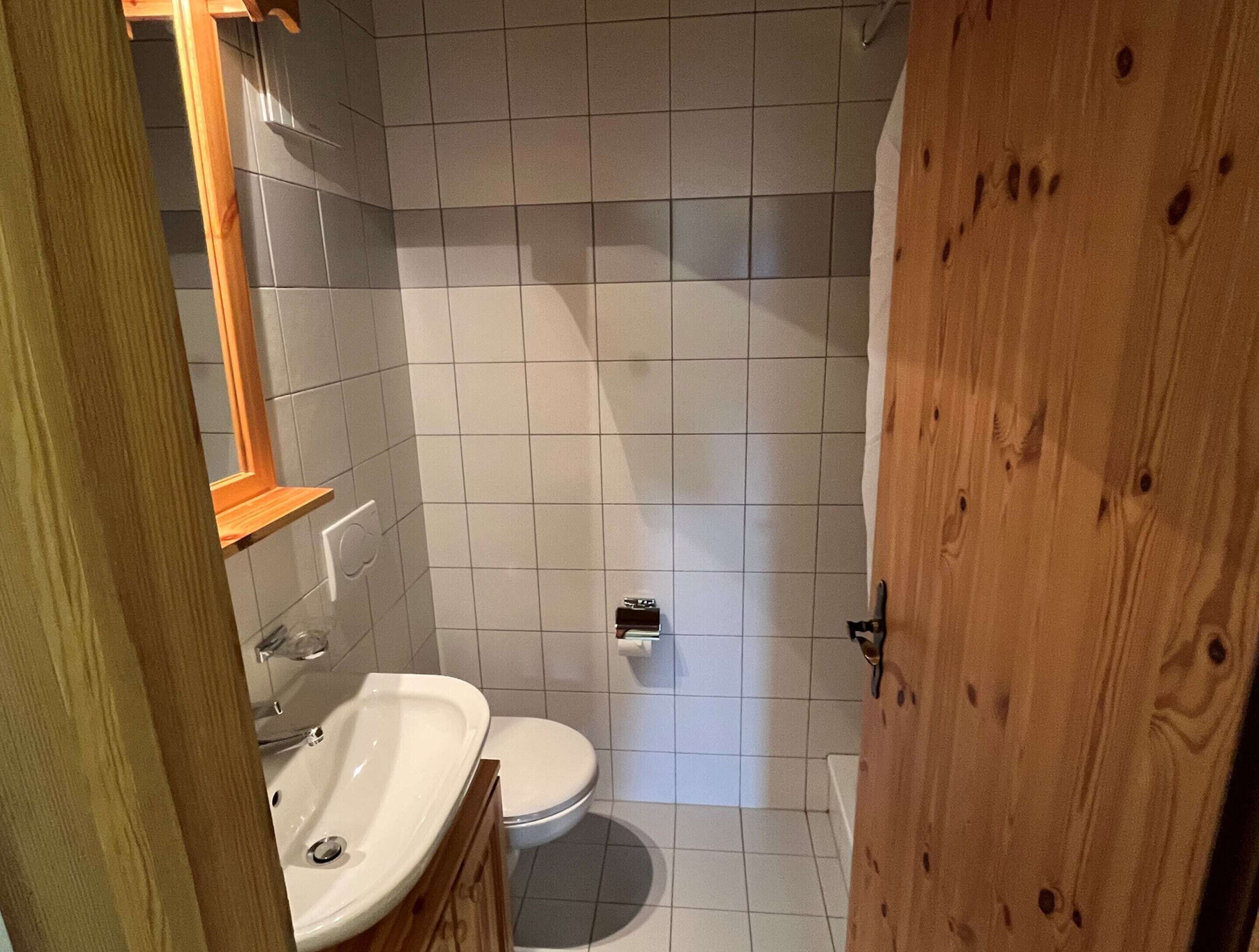 Un baño pequeño con inodoro, lavamanos y espejo.