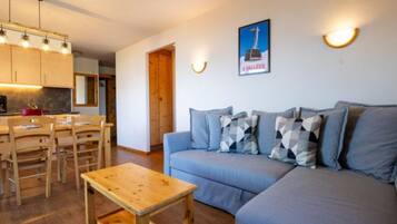 A cozy living room with a sofa, a wooden coffee table, and a dining area with a table and chairs.