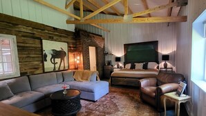 A cozy room with a large bed, a sofa, a leather armchair, and a coffee table. - Cozy loft inside a vintage store on an animal rescue farm in Westville, IN (Westville)