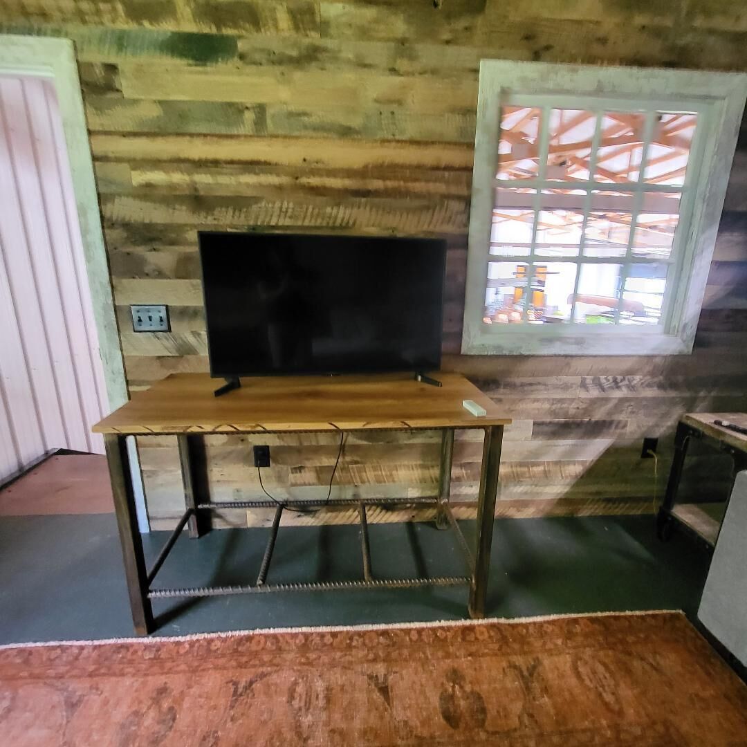 A room with a wooden wall, a window with a grid pattern, and a TV on a wooden table.