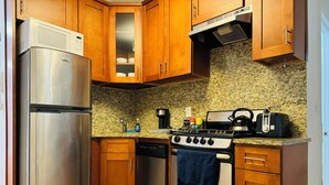 A kitchen with wooden cabinets, a stainless steel refrigerator, a dishwasher, a stove, and a microwave.