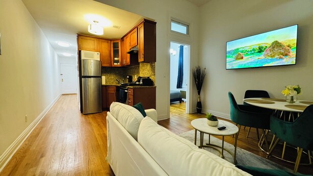 A modern kitchen with wooden cabinets, a stainless steel refrigerator, and a dining area with a round table and chairs.