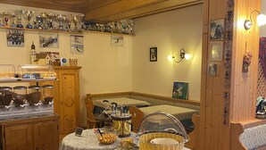 A cozy room with wooden furniture, a buffet setup with food and drinks, and a wall decorated with trophies and pictures.