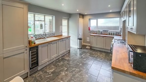 Une cuisine moderne avec des meubles gris, un sol en marbre et une grande fenêtre qui laisse entrer la lumière naturelle.