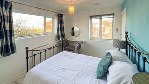Une chambre à coucher avec un lit, une chaise, un miroir et deux fenêtres.