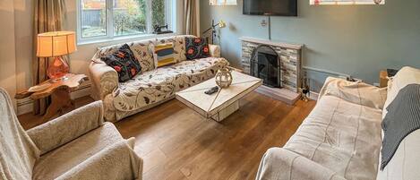 Una sala de estar con sofá, sillones, una mesa de centro, chimenea y televisor.