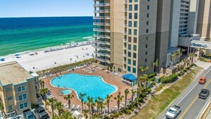 A hotel with a pool, beach, and ocean view.