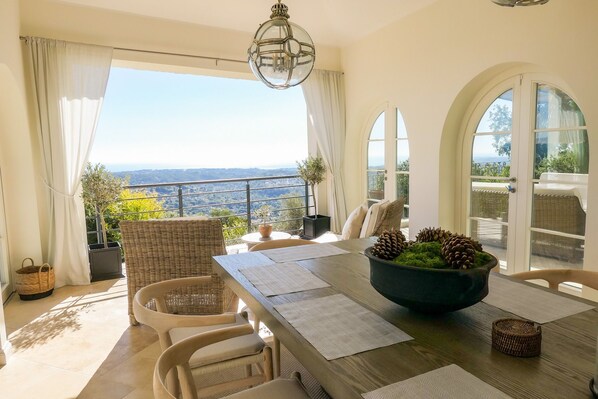 A dining area with a view of the landscape, wicker furniture, and a table with pinecones.