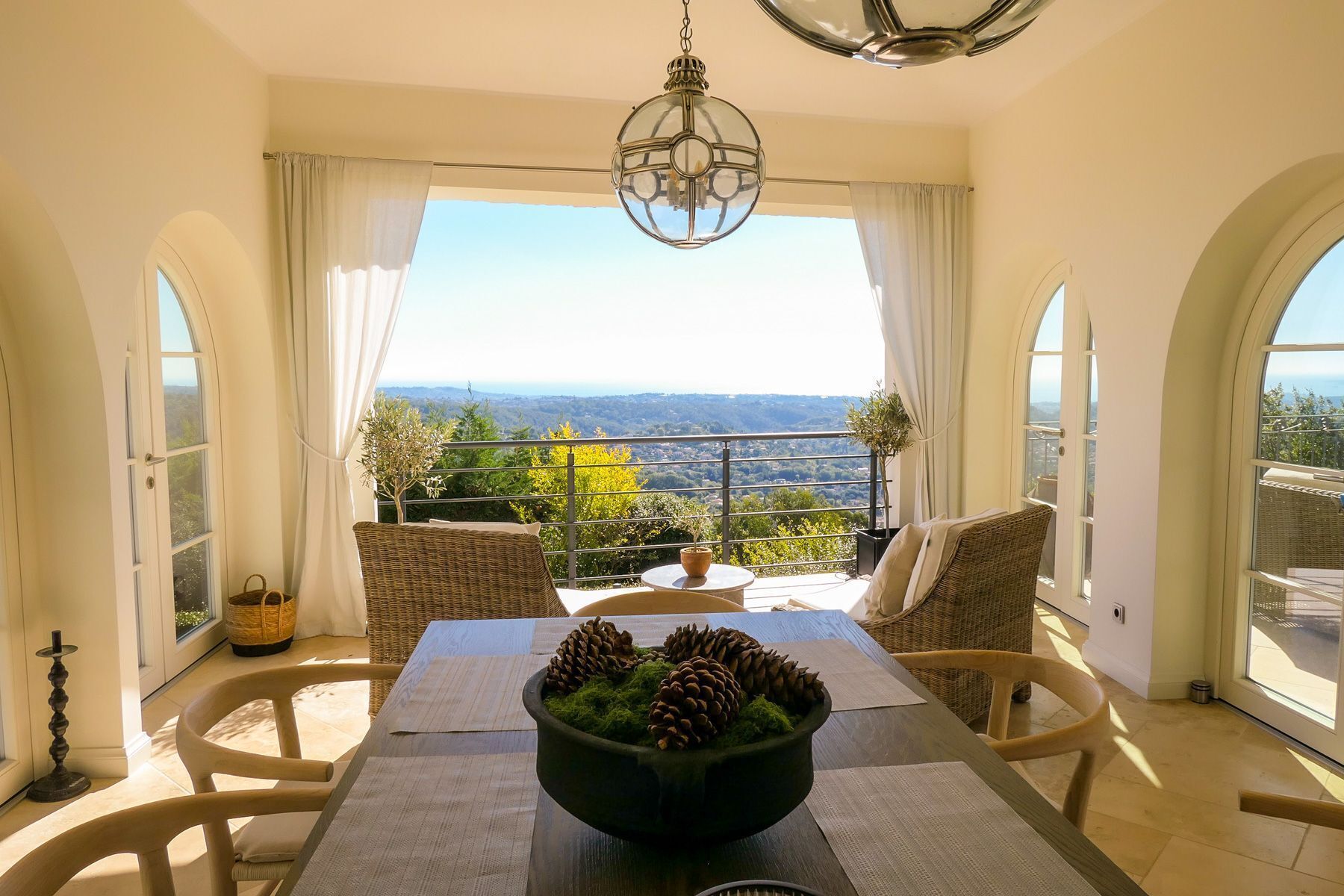 A dining area with a table, chairs, a chandelier, and a view of the landscape.