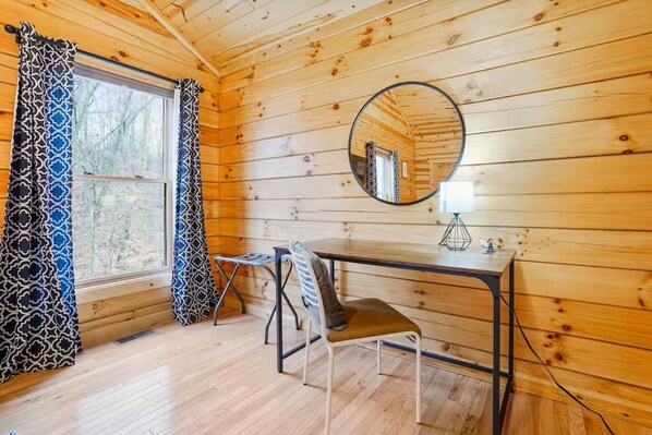 Habitación de cabaña de madera con escritorio, silla y espejo en la pared.