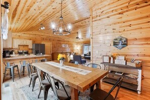 Interior de una cabaña de madera con comedor, cocina y sala de estar.
