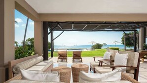 A spacious outdoor seating area with wicker furniture and a view of the ocean.
