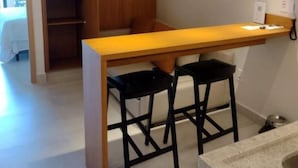 A compact kitchen with a wooden countertop, two black stools, and a hanging pendant light. - SMART apartment. High floor 14. Balcony with sea view. Salinas Premium Resort. (Salinópolis)