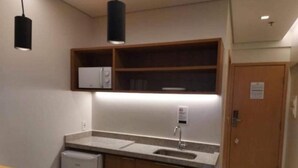 A compact kitchen with a built-in refrigerator, a sink, and wooden cabinets. - SMART apartment. High floor 14. Balcony with sea view. Salinas Premium Resort. (Salinópolis)