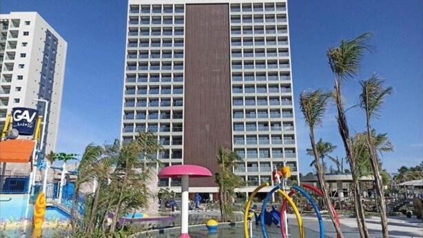 A hotel with a large building, palm trees, and a water play area with colorful structures. - SMART apartment. High floor 14. Balcony with sea view. Salinas Premium Resort. (Salinópolis)