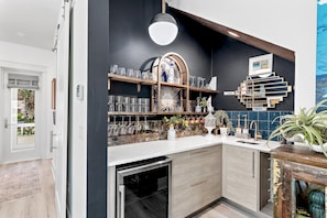 Uma cozinha moderna com forno embutido, pia e prateleira decorativa com copos.
