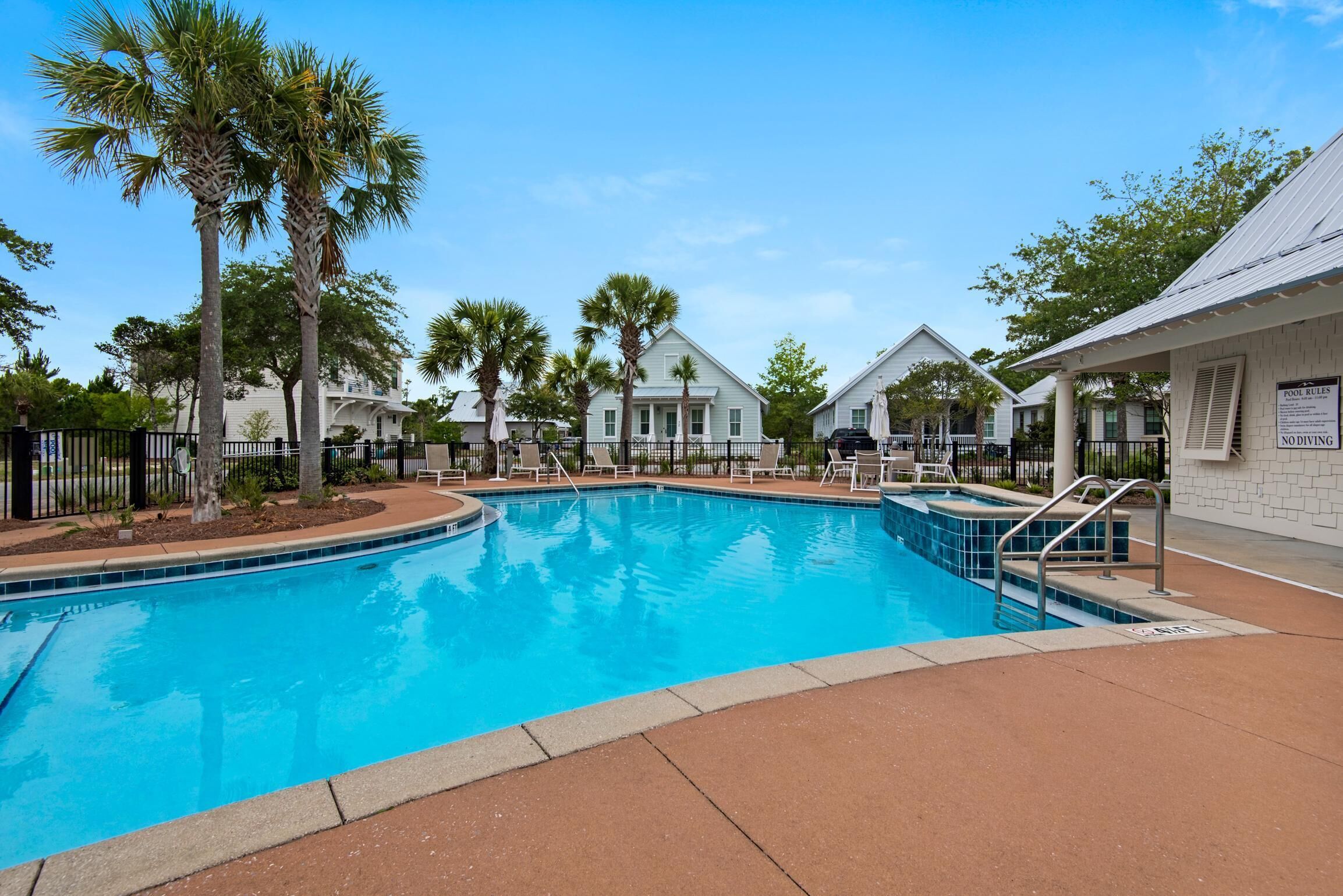 A swimming pool surrounded by palm trees and white buildings with a sign indicating 'No Diving'.