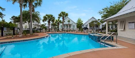 A swimming pool surrounded by palm trees and white buildings with a sign indicating 'No Diving'.