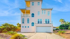 Une maison à plusieurs étages avec un garage, des balcons et un ciel dégagé.